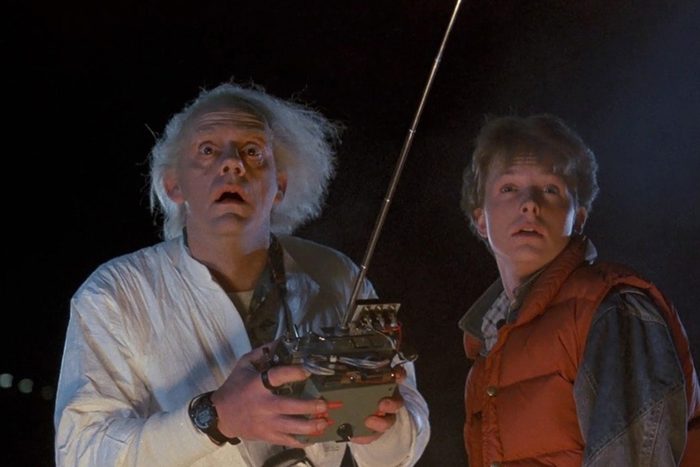 Two people hold a remote control, looking astonished. They're outdoors at night, surrounded by darkness.