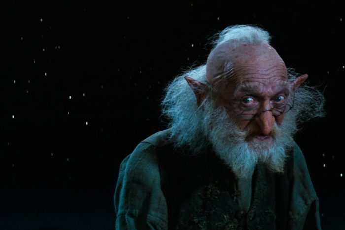 An elderly figure with pointed ears gazes intently, surrounded by a starry night sky.