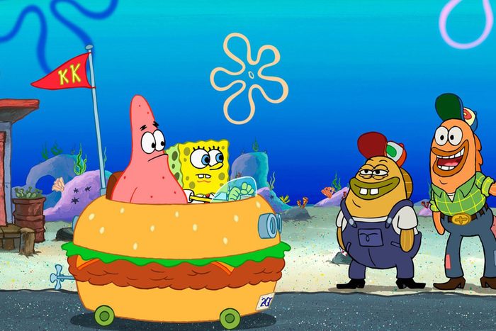Two animated characters drive a hamburger-shaped vehicle underwater, while two others stand nearby, smiling. A red flag reads 