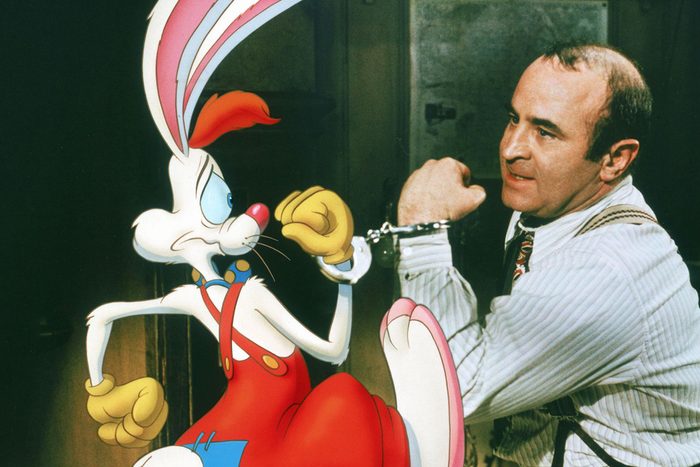 A cartoon rabbit and a man are handcuffed together in a dimly lit room, both appearing concerned.
