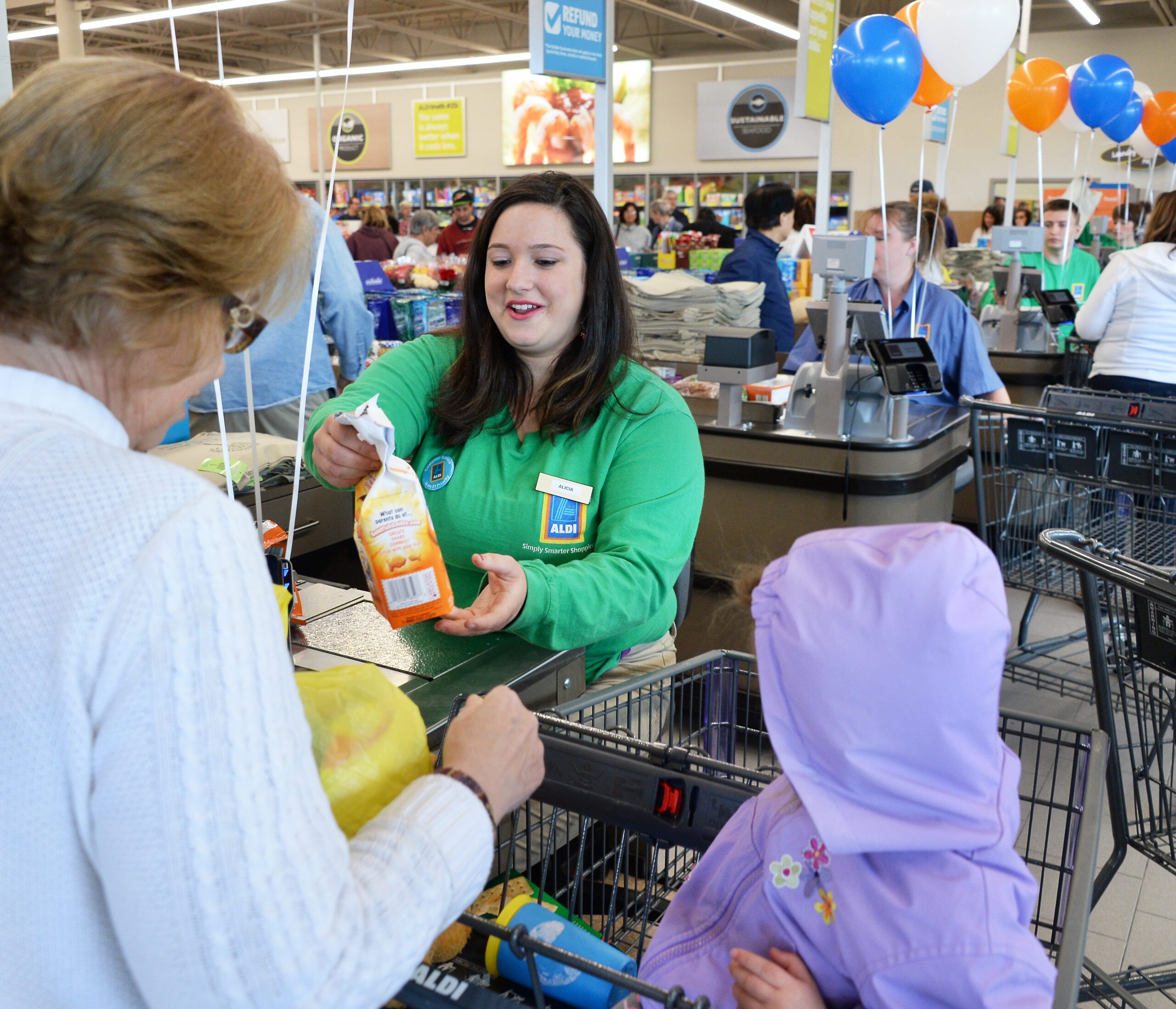 Aldi worker helps a customer check out with their groceries