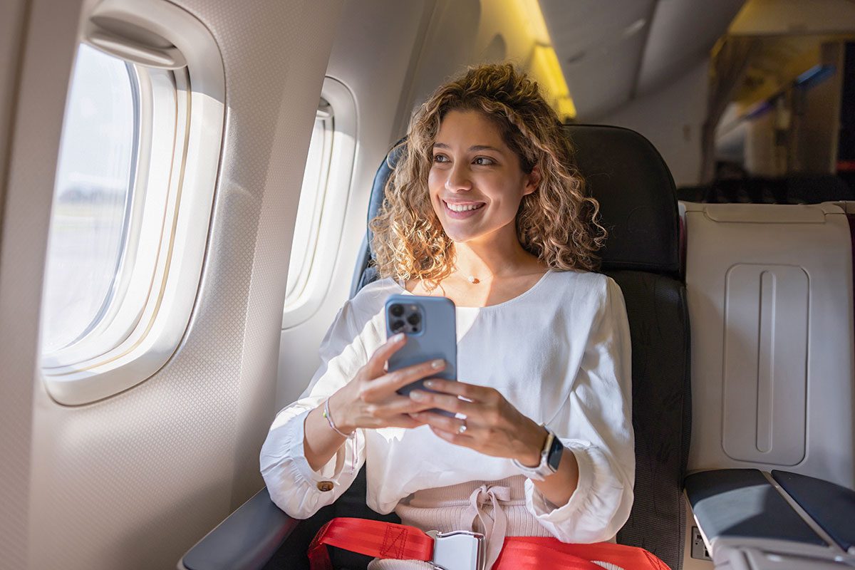 Female traveler using her cell phone in an airplane